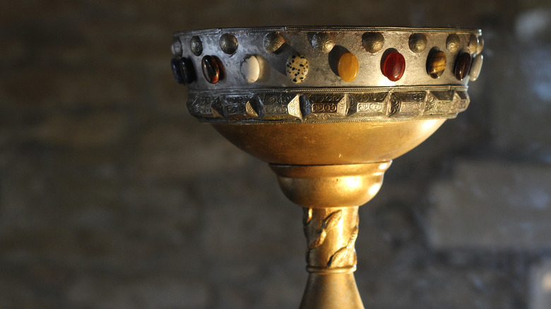 golden cup with jewels stone background