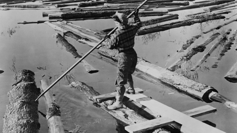 female lumberjack drives logs with pike pole during World War 2