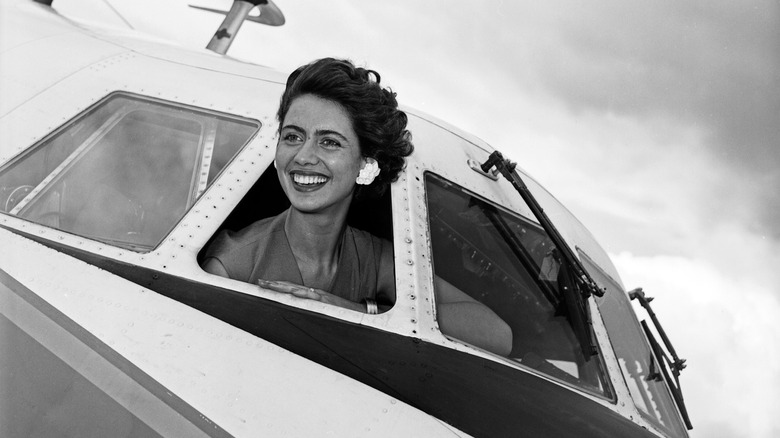 woman with her head out of the window of an old plane