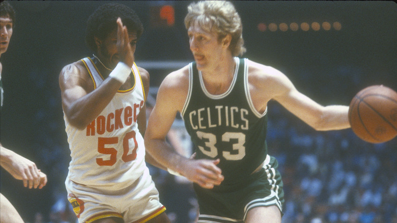 Larry Bird dribbling the ball on court players behind him