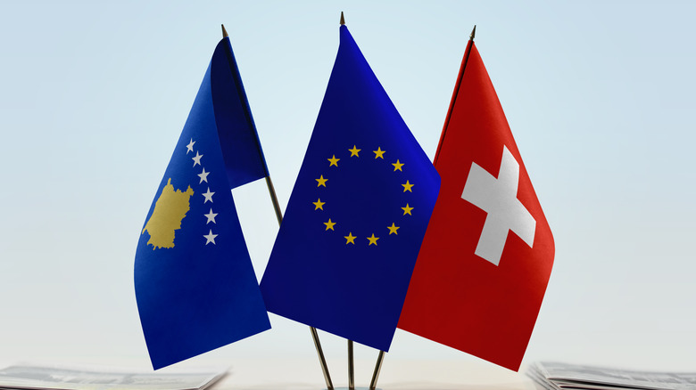 Kosovo, EU, and Swiss flags on desk with papers