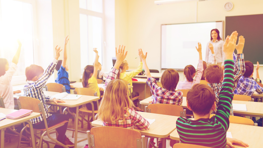 Kids raising their hands in school to ask questions about the metric system