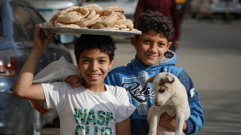 two boys in cairo holding plate of bread and a dog