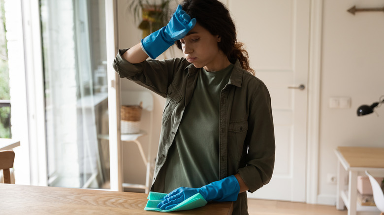 Tired woman doing chores in rubber gloves