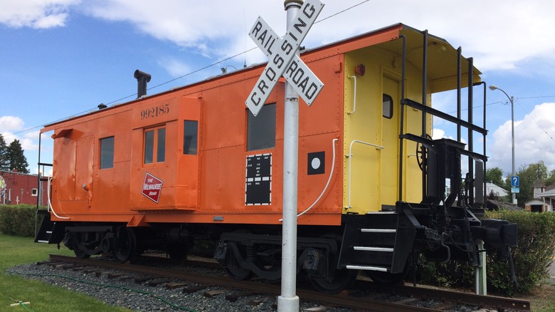 caboose idles by a crossing