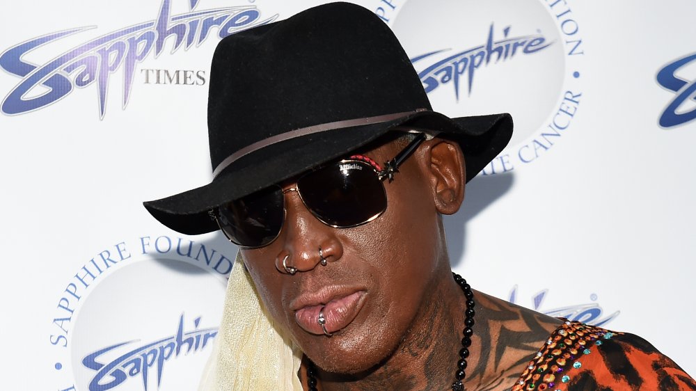 A close-up shot of Dennis Rodman wearing a black hat and dark sunglasses