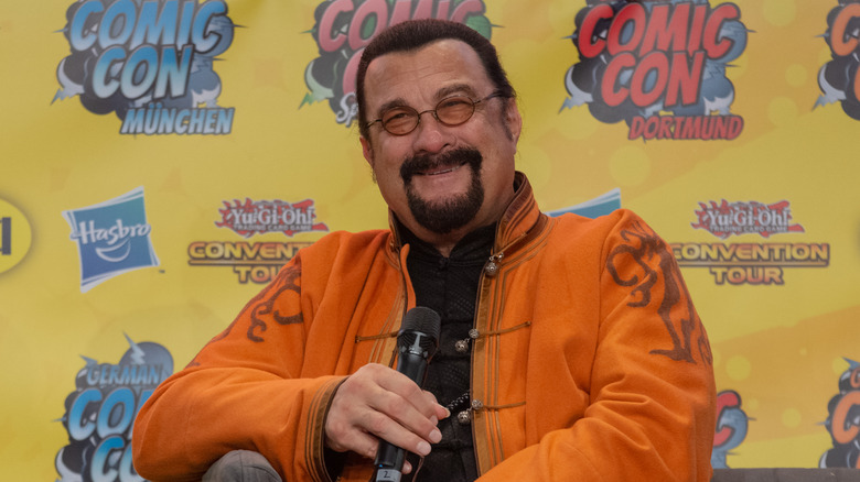 Steven Seagal smiling holding microphone