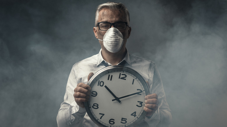 Man holding clock and wearing mask