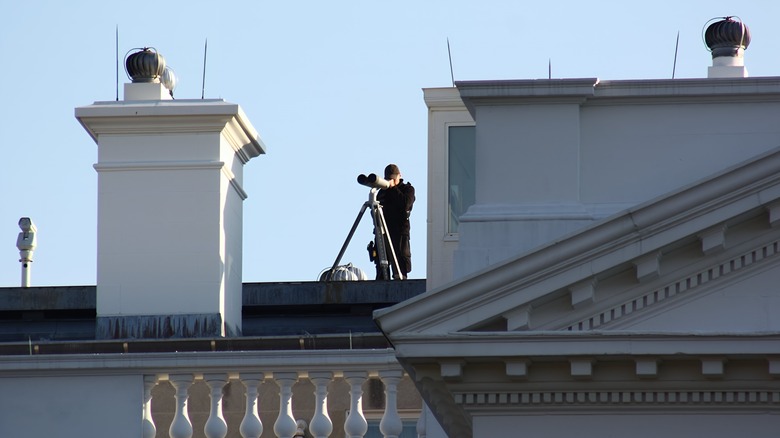 Secret Service agent with binoculars on White House roof