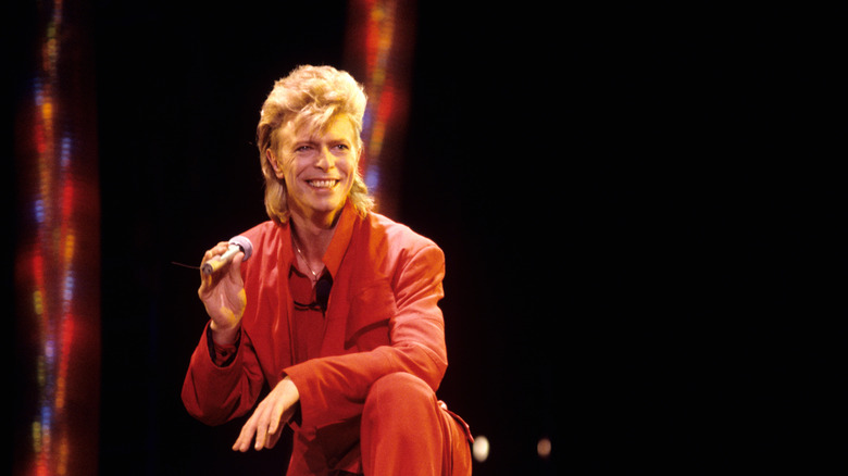 David Bowie in red suit smiling with microphone