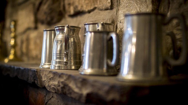 Pewter tankards on stone ledge