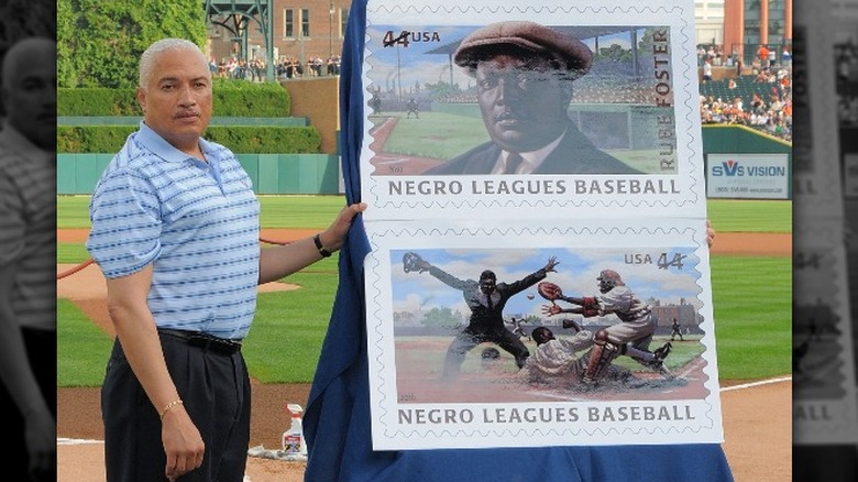 Man blue polo unveiling large poster of stamps outside