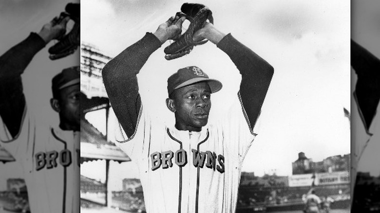 Satchel Paige standing holding baseball in glove above head