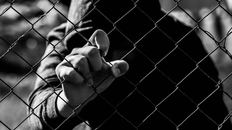 Teen in hoodie holding fence