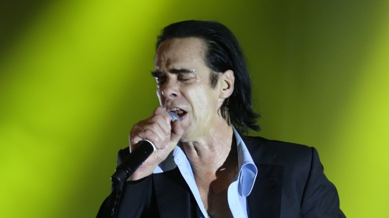 Nick Cave performs holding microphone