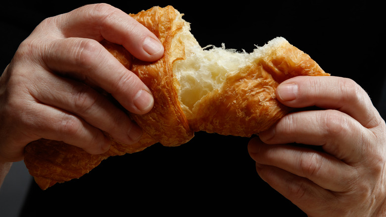 person's hands breaking bread