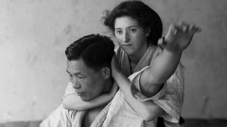 Young woman has her jiu jitsu instructor in a headlock, circa 1906