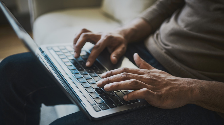 A man typing on a laptop in a darkened room