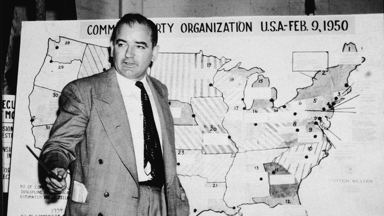 Senator Joe McCarthy posing with evidence during a hearing