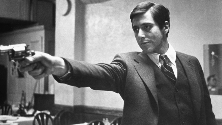 Al Pacino stretches out arm while holding gun as Michael Corleone