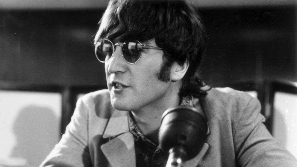 John Lennon speaking at a microphone