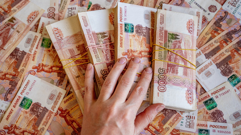 Hand on Russian ruble bill stacks