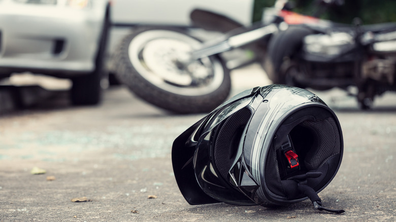 Helmet on road with motorbike and car in background