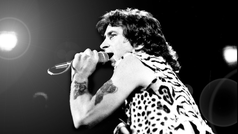 bon scott singing into a microphone on stage