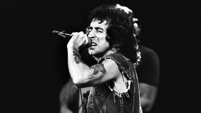 bon scott in denim jacket singing on stage