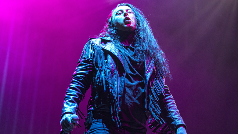 Ronnie Radke wearing a black jacket and holding a mic while on stage