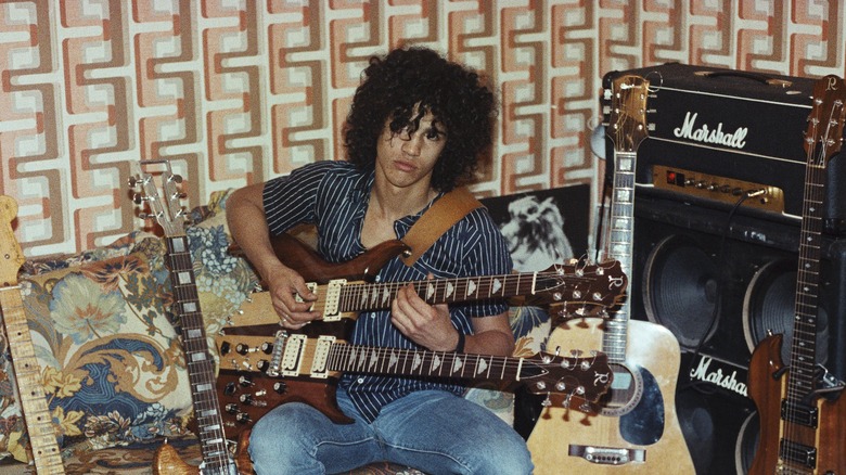 Slash sat surrounded by guitars