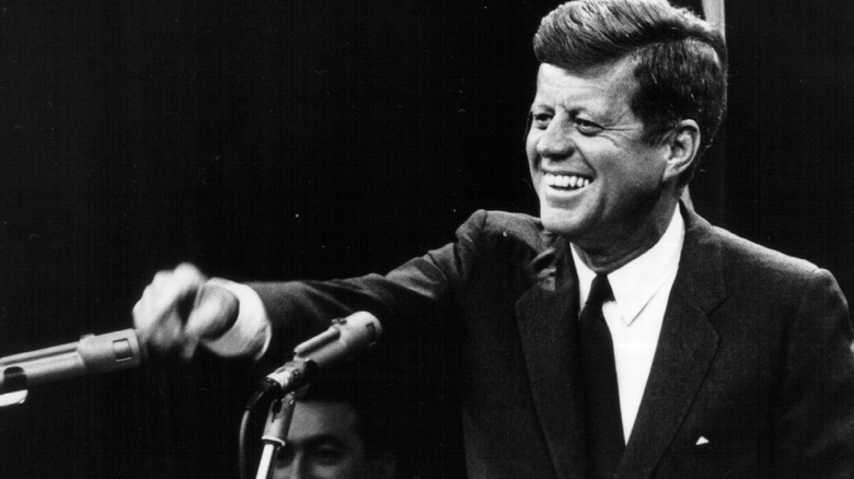 John F. Kennedy laughing at a podium during a press conference