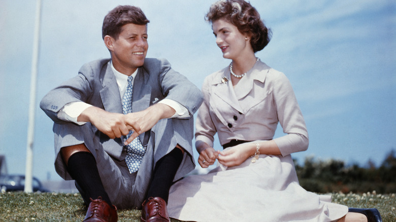 John and Jackie Kennedy sitting on the grass outside