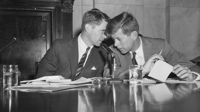 Robert and John F Kenndy sitting at a desk talking