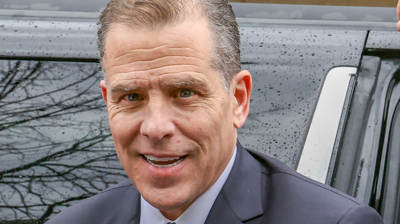 Hunter Biden smiling in front of a car