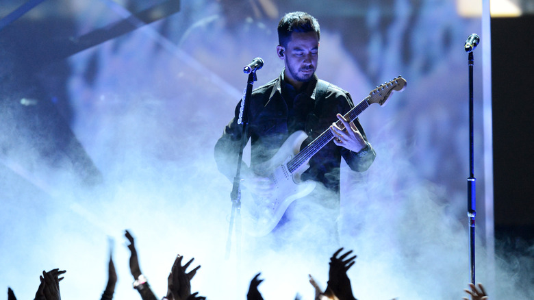 Mike Shinoda playing guitar on smoky stage