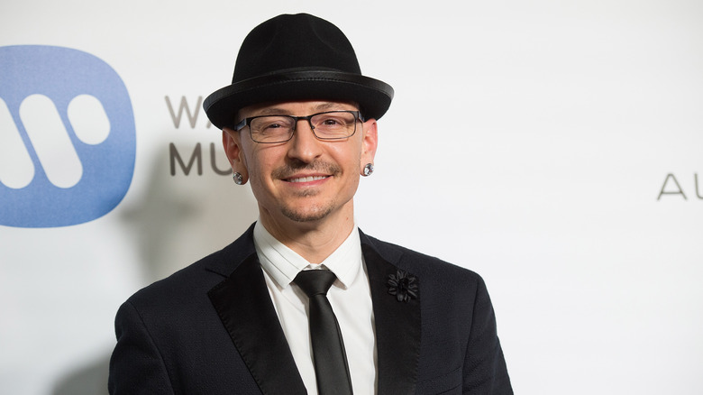 Smiling Chester Bennington wearing black hat and suit