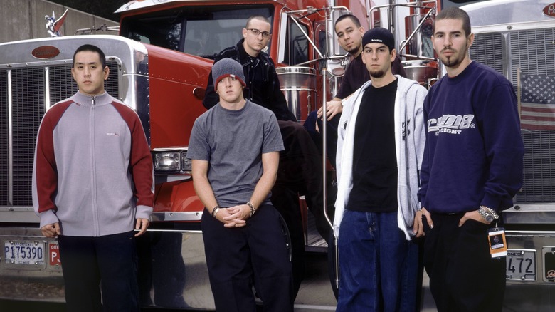 Linkin Park posing in front of two trucks