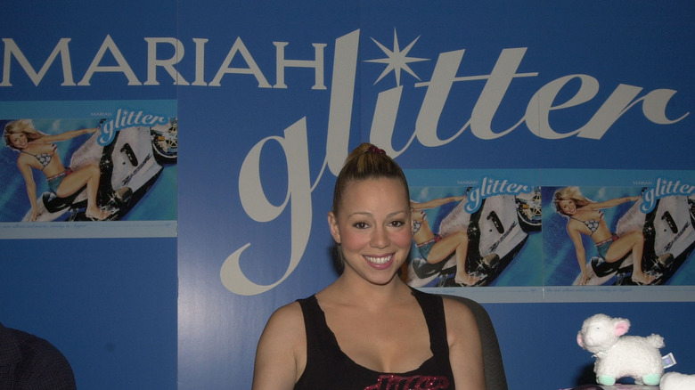 mariah carey sitting in front of glitter promo wall