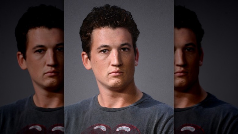 Miles Teller wearing gray shirt and looking serious