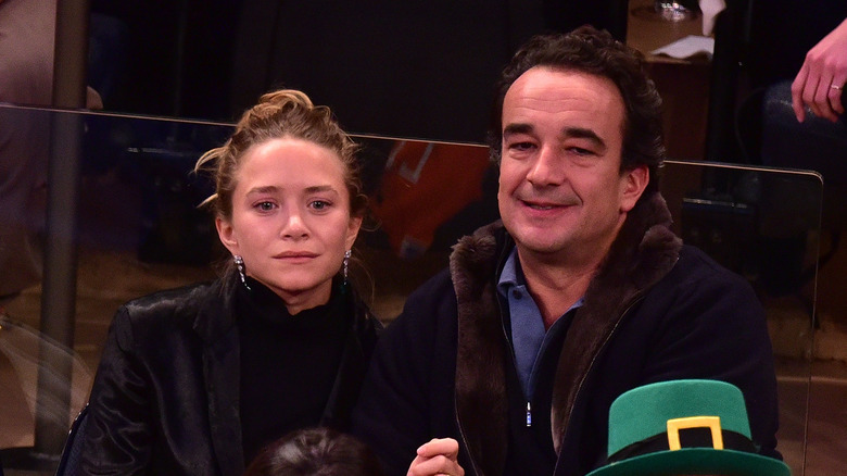 Mary-Kate Olsen and Olivier Sarkozy sitting at a basketball game