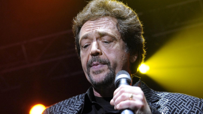 jay osmond looking down while holding microphone onstage