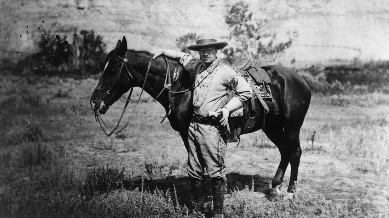 Theodore roosevelt stands next to horse