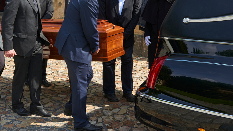 People bringing coffin towards hearse