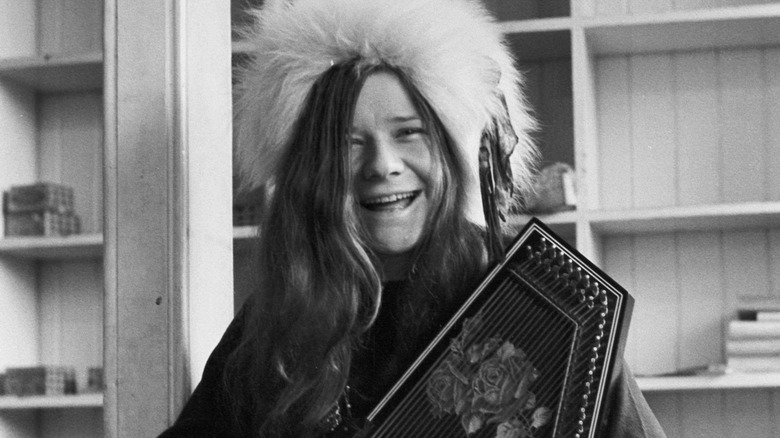 Janis Joplin smiling and holding an instrument