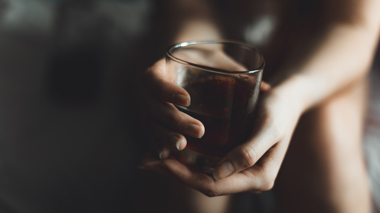 Hands holding glass of whiskey