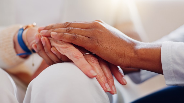 Elderly person holding doctor's hand