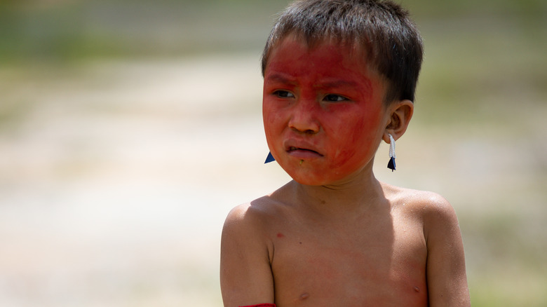 Yanomami boy red face paint earrings