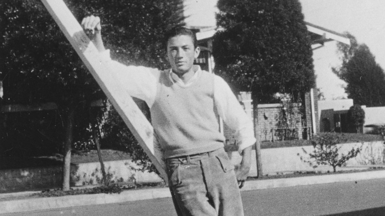 A young Gregory Peck standing outside