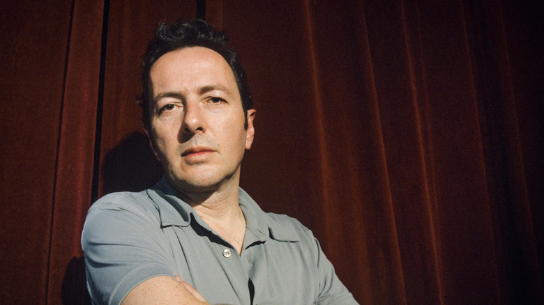 Joe Strummer by curtain arms crossed